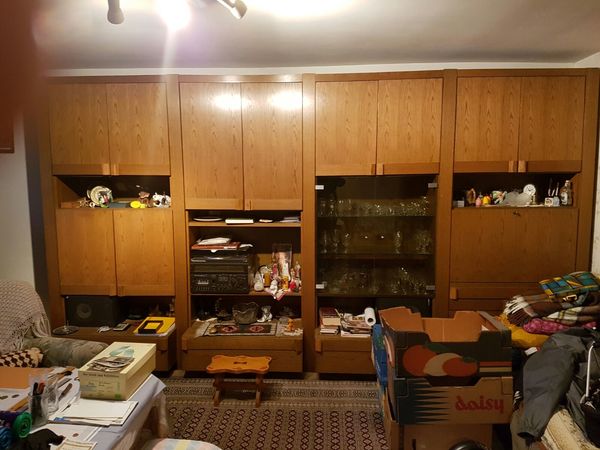 Großer Wohnzimmerschrank aus Holz mit Glastüren, Dekoration, Kartons und Haushaltsgegenständen.