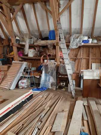 Dachboden mit Holzlatten, Werkzeug, Leiter und Baumaterialien für Renovierungsarbeiten.