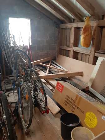Dachboden mit alten Fahrrädern, Holzlatten, Kartons und Schinken an Holzbalken.