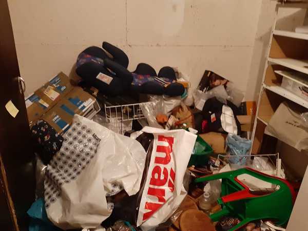 Kellerraum mit Unordnung, Kartons, Tüten, Regalen und verschiedenen Haushaltsgegenständen.